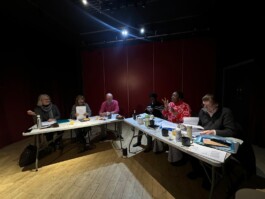 six people sitting around two tables arranged in a V shape 